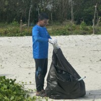 teenage boy dumping waste to a black bag