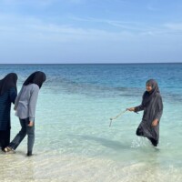 teen carrying a small twig from the lagoon to clean ocean