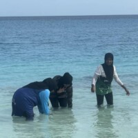 teenagers standing in a lagoon and cleaning