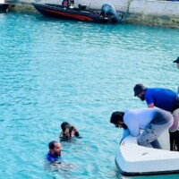 people on a speed boat talking to people swimming in a lagoon