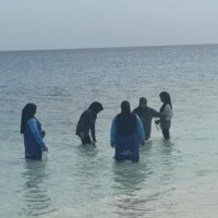 Teenagers standing in a lagoon in Maldives Thimarafushi island
