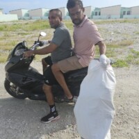 man carrying a bag of trash on a motor bike