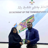 Man giving a staff card and uniform to an old lady