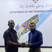 Two people staring at the camera holding a folded cloth and a card