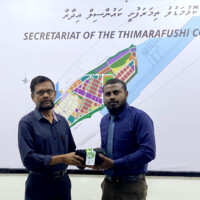 man handing a folded uniform to another man