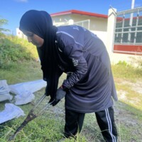 woman with a large scissor cutting grass